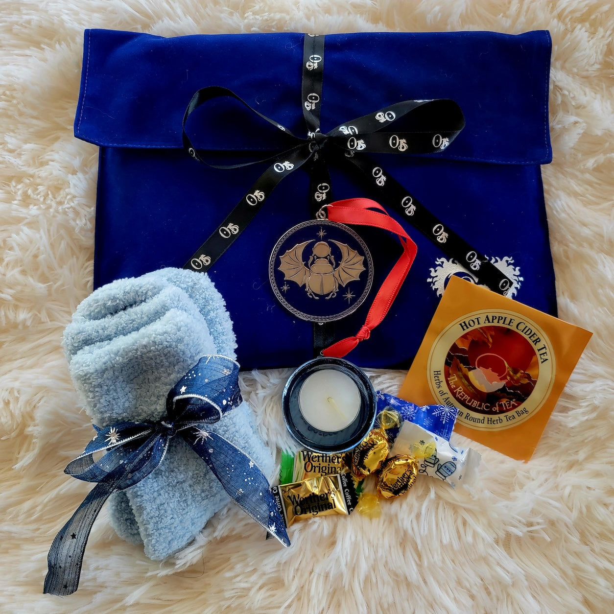 Blue suede gift bag with scarab ornament, fuzzy socks, tea, candy and tealight
