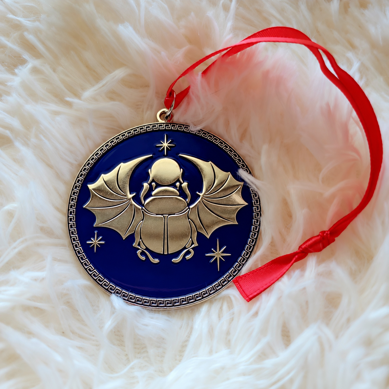 Custom enamel scarab ornament on a red ribbon
