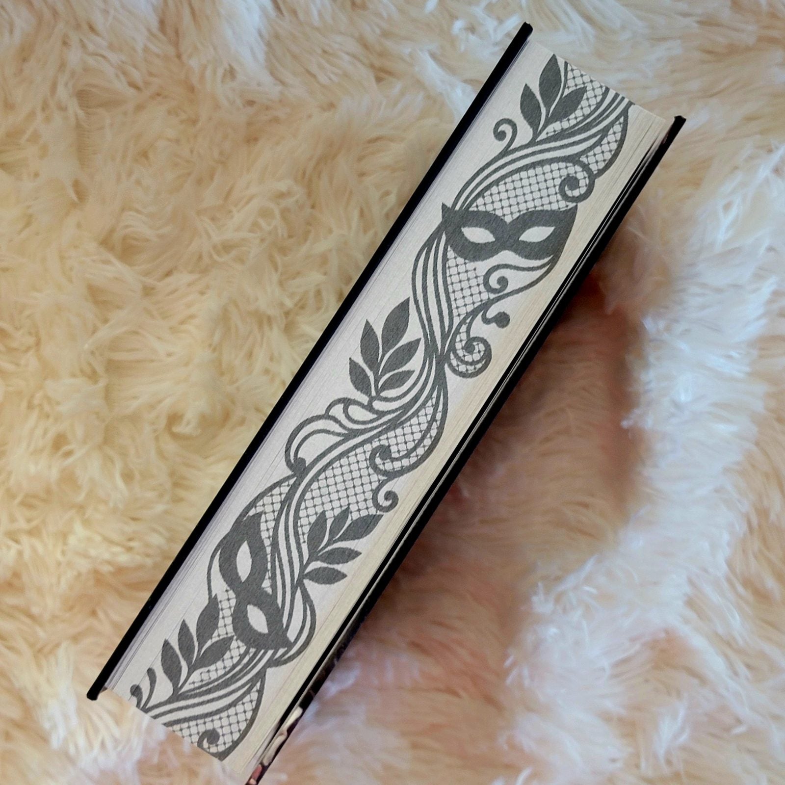 Close-up of the lace and masquerade-mask page edge design